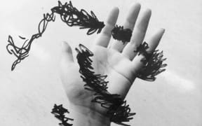 A hand is obscured by black scribbles, to illustrate struggles with mental health