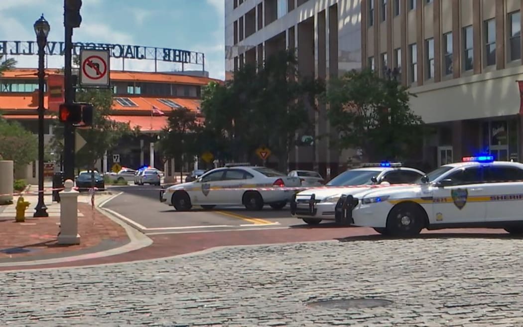 Police cars block a street leading to the Jacksonville Landing area in downtown Jacksonville after a mass shooting at a video game tournament.