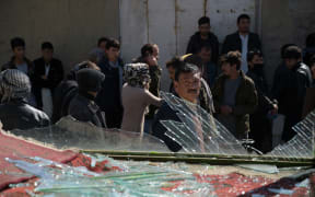 People walk past the site of a suicide car bombing; one of two Taliban attacks in Kabul on the same day.