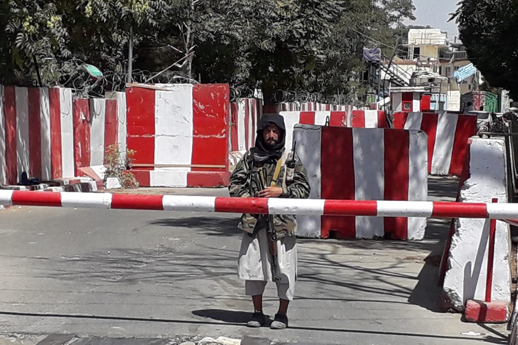 A Taliban fighter stands guard at the entrance of the police headquarters in Ghazni, on 12 August 2021, as Taliban move closer to Afghan capital after taking Ghazni city.