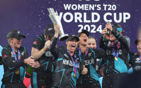 New Zealand White Ferns captain Sophie Devine lifts the trophy as players celebrate winning the Women's T20 World Cup. 2024.