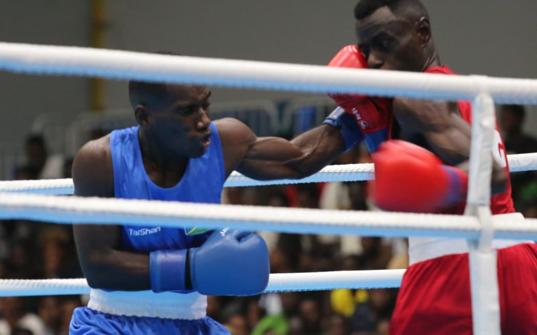 Pacific Games boxing round of 16:  Solomon Islands boxer Maximillian Makana’s (blue) left hook featured prominently in his 4-1 split decision win over Floyd Kunnopi from Papua New Guinea. Friendship Hall Honiara 27 November 2023 credit RNZ Pacific/Koroi Hawkins