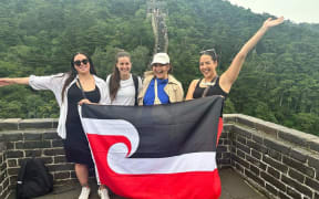 曾经学习中文的投资顾问Jamie Erin Wood（左二）和同伴在长城上展示毛利旗帜。她说，此次行程提醒她，她有多么喜欢学习中国语言和文化。