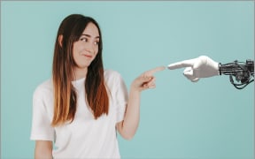 An image of a human pointing at a robotic arm.