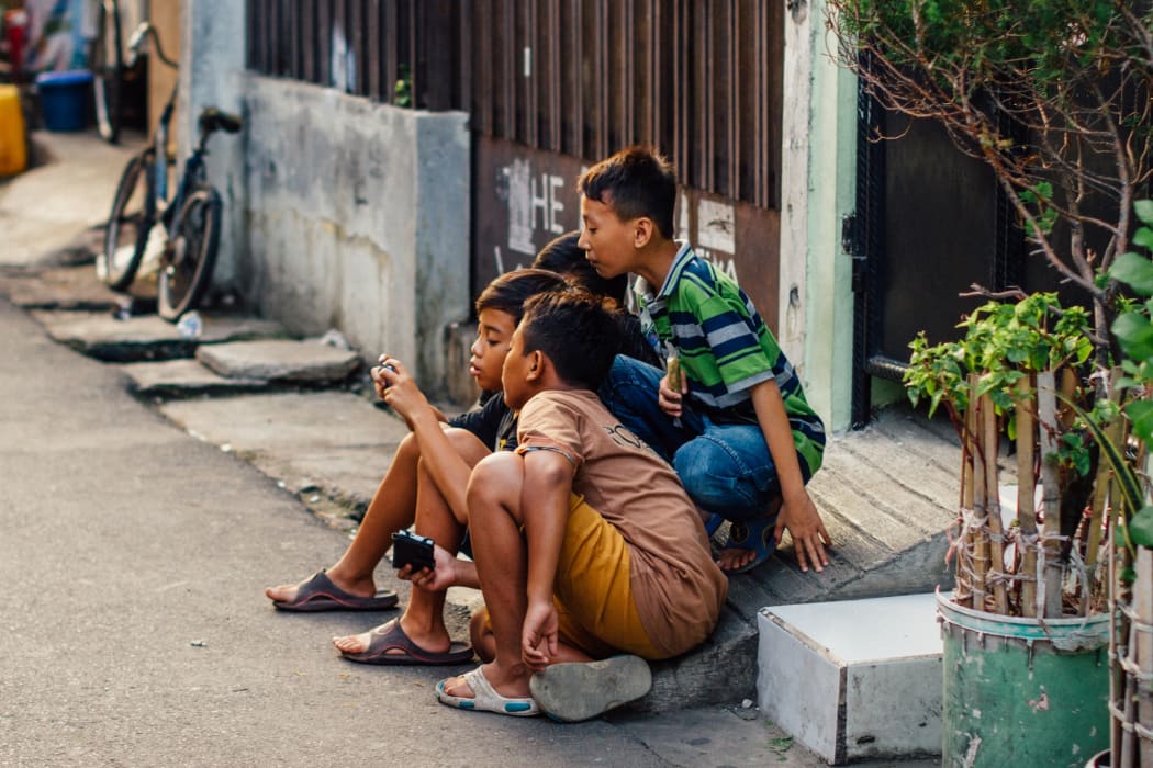 Three boys crowd around a mobile phone