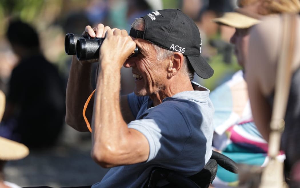 A fan uses binoculars to get a close up view of the racing.
