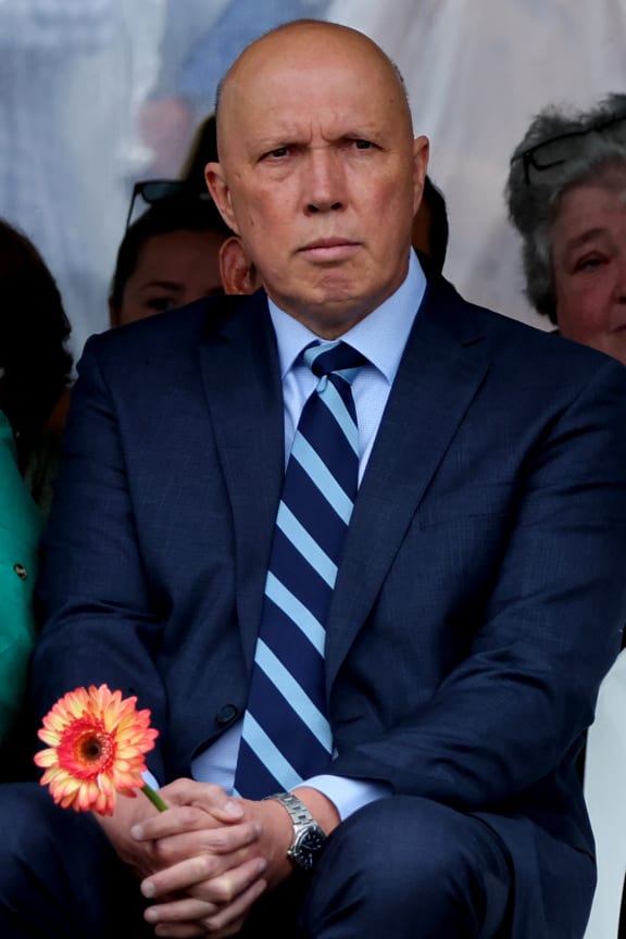 Australia's opposition leader Peter Dutton holds a flower as he attends a commemoration ceremony to mark the 20th anniversary of the Bali bombings, at Coogee Beach in Sydney on October 12, 2022. (Photo by DAVID GRAY / AFP)