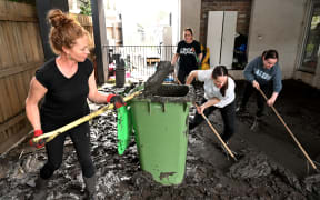 People clear mud from a property damaged by floods in the Melbourne suburb of Maribyrnong on 15 October, 2022.