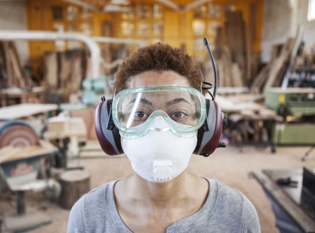 [USA] Close up view of black woman factory worker wearing safety glasses and dust nose mask in a woodworking factory. (Photo by Mint Images / Mint Images / Mint Images via AFP)