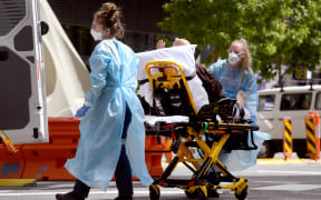 Medical staff stretchering a patient at Royal Melbourne Hospital. The state's surge in infection numbers has put pressure on the state's health system.