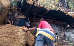 Locals look into a demolished house at the site of a landslide at Yambali Village in the region of Maip Mulitaka, in Papua New Guinea's Enga Province on May 25, 2024.