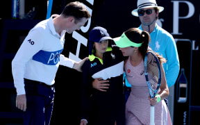 Turkey’s Zeynep Sonmez assists a ball kid after she fainted during Sonmez’s women’s singles match against Russia’s Ekaterina Alexandrova on day one of the Australian Open in Melbourne on January 18, 2026. (Photo by DAVID GRAY / AFP) / -- IMAGE RESTRICTED TO EDITORIAL USE - STRICTLY NO COMMERCIAL USE --