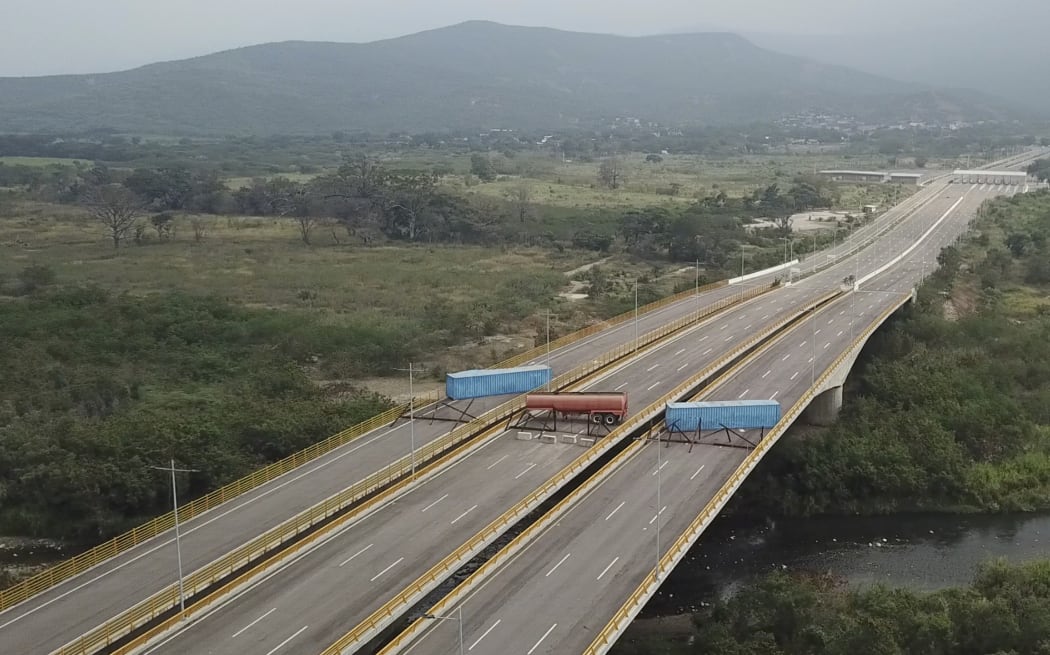 This image taken from video, shows a fuel tanker, cargo trailers and makeshift fencing, blocking the Tienditas International Bridge in an attempt to stop humanitarian aid entering from Colombia,