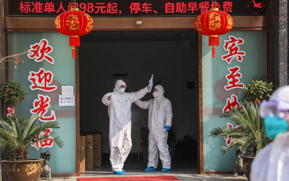 Medical staff member (left) being disinfected by a colleague before leaving a quarantine zone converted from a hotel in Wuhan, 3 February 2020.