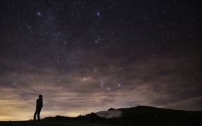 A photographer looks at the sky at night to see the annual Geminid meteor shower in northern Italy.