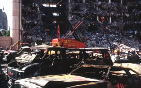 The bombed remains of automobiles with the bombed Federal Building in the background.  The military is providing around the clock support since a car bomb exploded inside the building on Wednesday, April 19, 1995.