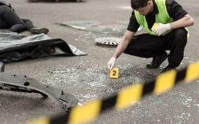 A policeman inspects a road after a crash.