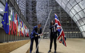 EU Council staff members remove the United Kingdom's flag from the European Council building in Brussels.