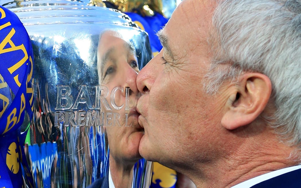 Leicester manager Claudio Ranieri is reflected in the silver as he kisses the EPL trophy.