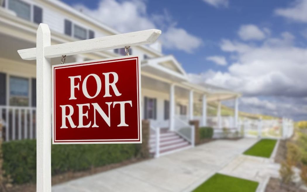 For rent sign in front of two-storey houses.