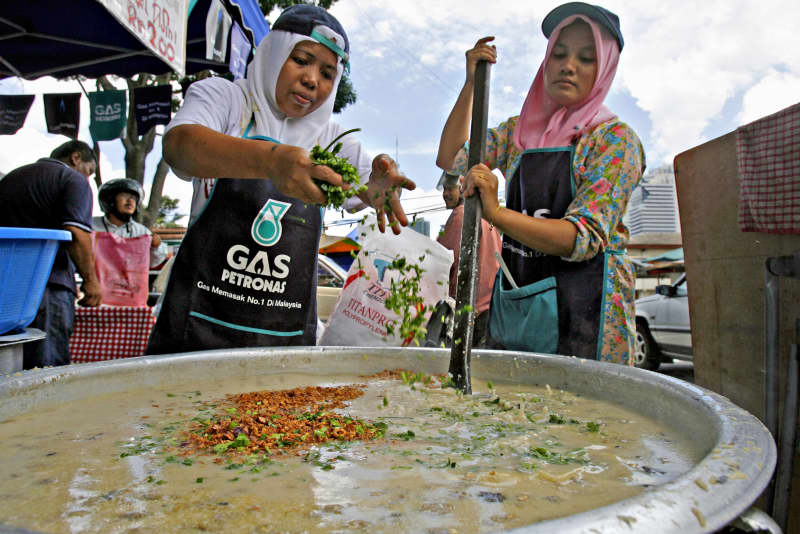 A woman adds scallions to a pot of 'bubur lambuk', a traditional rice porridge dish prepared during the Muslim fasting month of Ramadan, in downtown Kuala Lumpur, on 2 October, 2006.