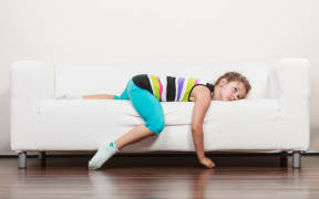 Tired exhausted lazy little girl lying on sofa at home. Sleepy kid resting relaxing on couch.