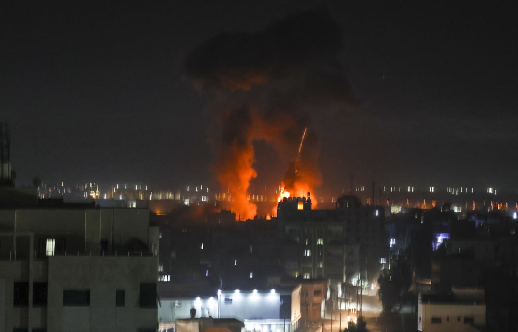 Explosions light up the night sky above buildings in Gaza City as Israeli forces shell the Palestinian enclave, early on 16 June 2021.
