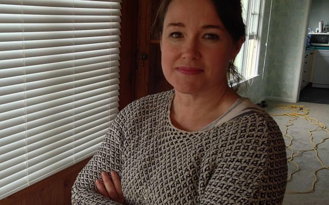 Woman stand in living room of a property she is insulating and carpeting.