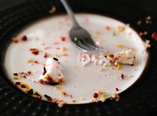A bunch of grains and leftover food sitting on a plate with a fork.