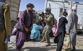 A US soldier point his gun towards an Afghan passenger at the Kabul airport on 16  August 2021, as thousands rushed to the airport after the Taliban seized power.