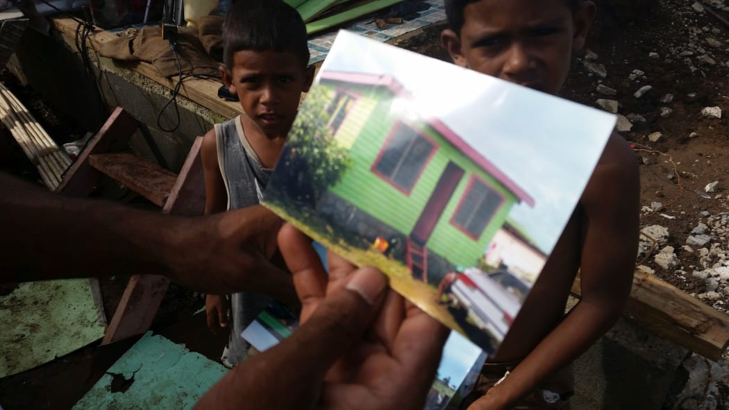 Mohammed Nadim shows photos of the house that was destroyed by Winston.