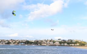 A kitesurfer catches some big air at Sandspit