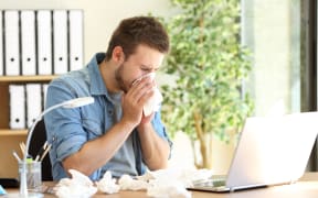 Portrait of a sick entrepreneur blowing in a wipe at office with a lot of used wipes on the desk