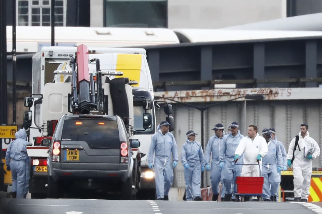 The white van used in the attack on London Bridge is hoisted on top of a flat-bed truck as police work on gathering evidence and securing the area.