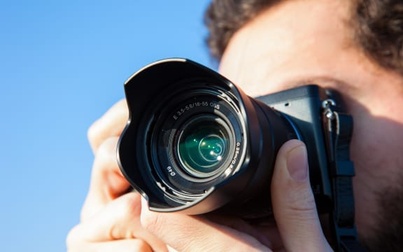 A photographer holds up his camera to take a shot (file)