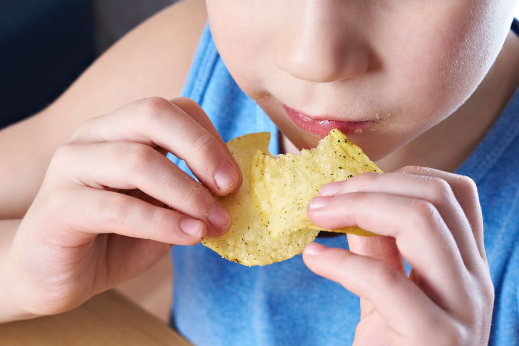 Little boy eating potato chips.