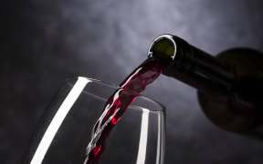 Red wine is poured from the bottle into a glass