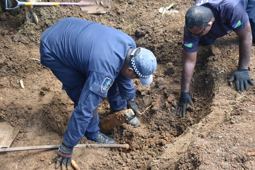 Solomon Islands police officers digging up WWII shells at Gilbert Camp in Honiara.