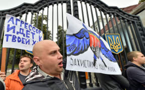 People hold placards "Aggressor comes to your house" and "Save our women" during the rally in front of the Ukrainian Defence Ministry in Kiev.
