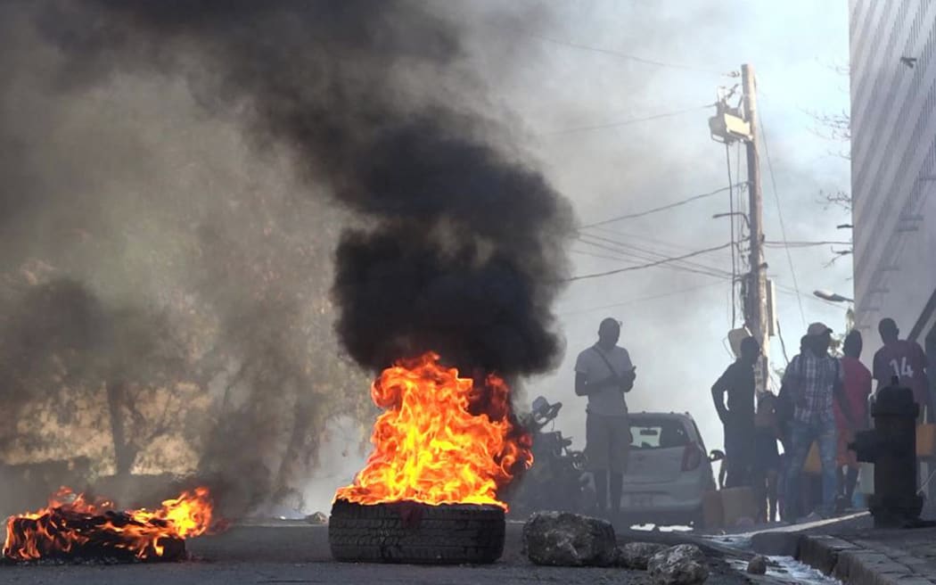This screen grab taken from AFPTV shows tires on fire near the main prison of Port-au-Prince, Haiti, on March 3, 2024, after a breakout by several thousand inmates. At least a dozen people died as gang members attacked the main prison in Haiti's capital, triggering a breakout by several thousand inmates, an AFP reporter and an NGO said on March 3. "We counted many prisoners' bodies," said Pierre Esperance of the National Network for Defense of Human Rights, adding that only around 100 of the National Penitentiary's estimated 3,800 inmates were still inside the facility after the gang assault overnight on March 2. (Photo by Luckenson JEAN / AFPTV / AFP)
