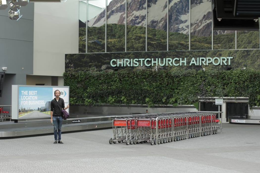 Hamish stqanding in front of a Christchurch airport baggage carousel