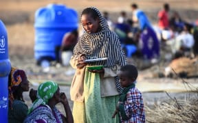 An Ethiopian refugee who fled intense fighting in their homeland of Tigray, speaks to a fellow refugee at the border reception centre of Hamdiyet, in the eastern Sudanese state of Kasala, on November 14, 2020.