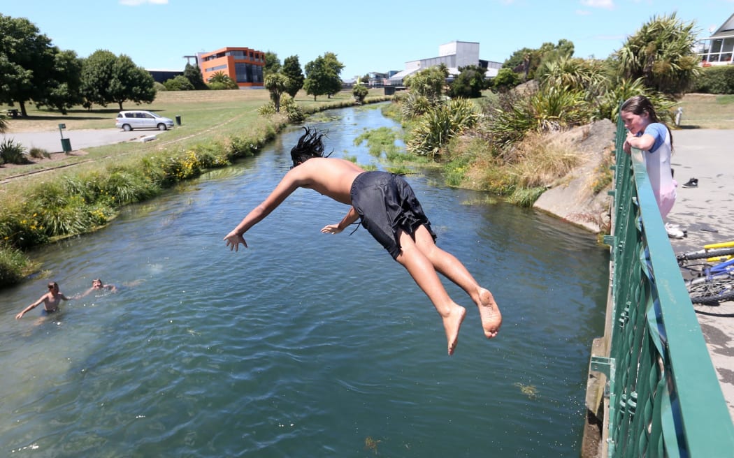 A kid in black shorts jumps into the Taylor River, in central Blenheim where there has been a significant reduction in bacteria.