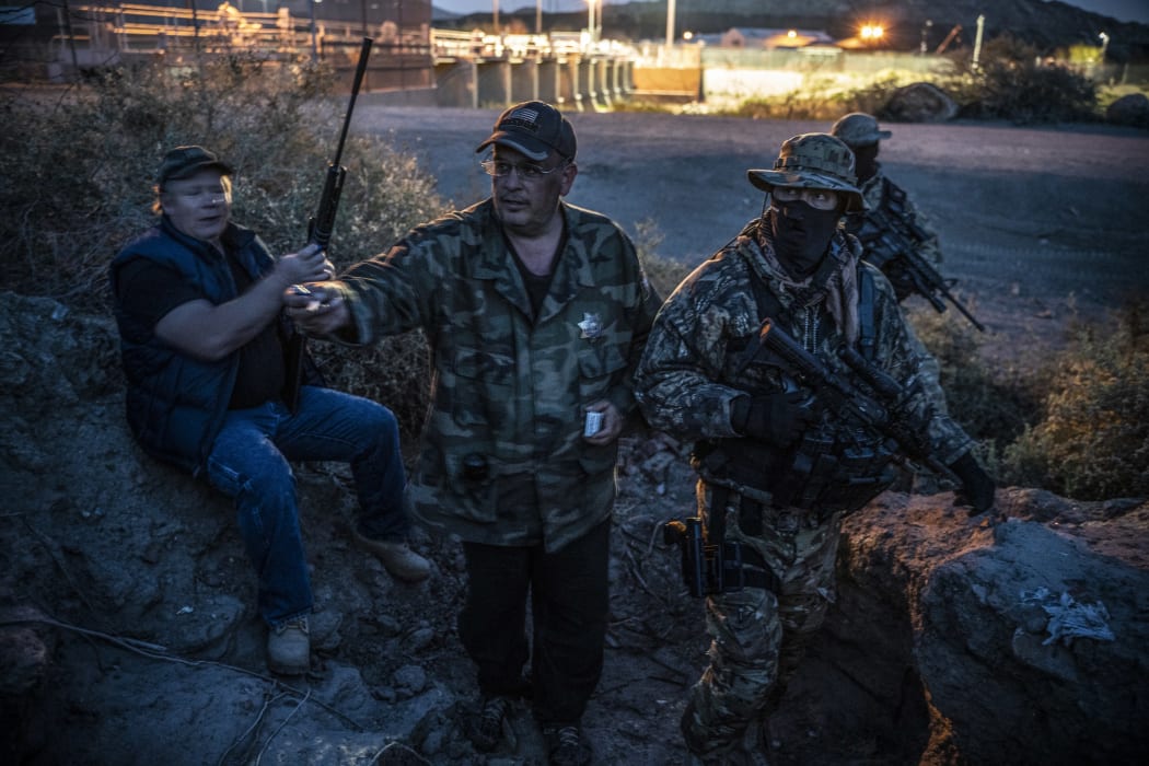 (FILES) In this file photo taken on March 20, 2019 Jeff Allen, Jim Benvie, Viper and Stinger share cigarettes while patrolling the US-Mexico border in Sunland Park, New Mexico on March 20, 2019.