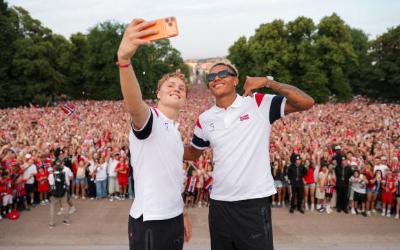 Norway footballers Andreas Schjelderup (L) and Antonio Nusa take a selfie in front of supporters at The Royal Palace after returning from the football World Cup. (Photo: Amanda Pedersen Giske / NTB)