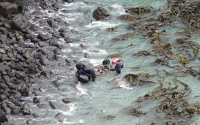 A helicopter lifted the wreck before dropping it closer to the cove's rocky shore.