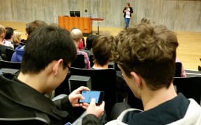 Two developers compare mobile phone apps at the Game Developers Conference.