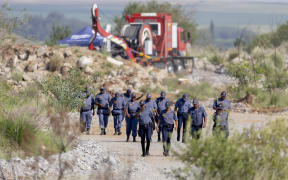 South African Police Service (SAPS) officers walk near a Metalliferous Mobile Rescue Winder during a rescue operation to retrieve illegal miners from an abandoned gold shaft in Stilfontein on January 13, 2025.