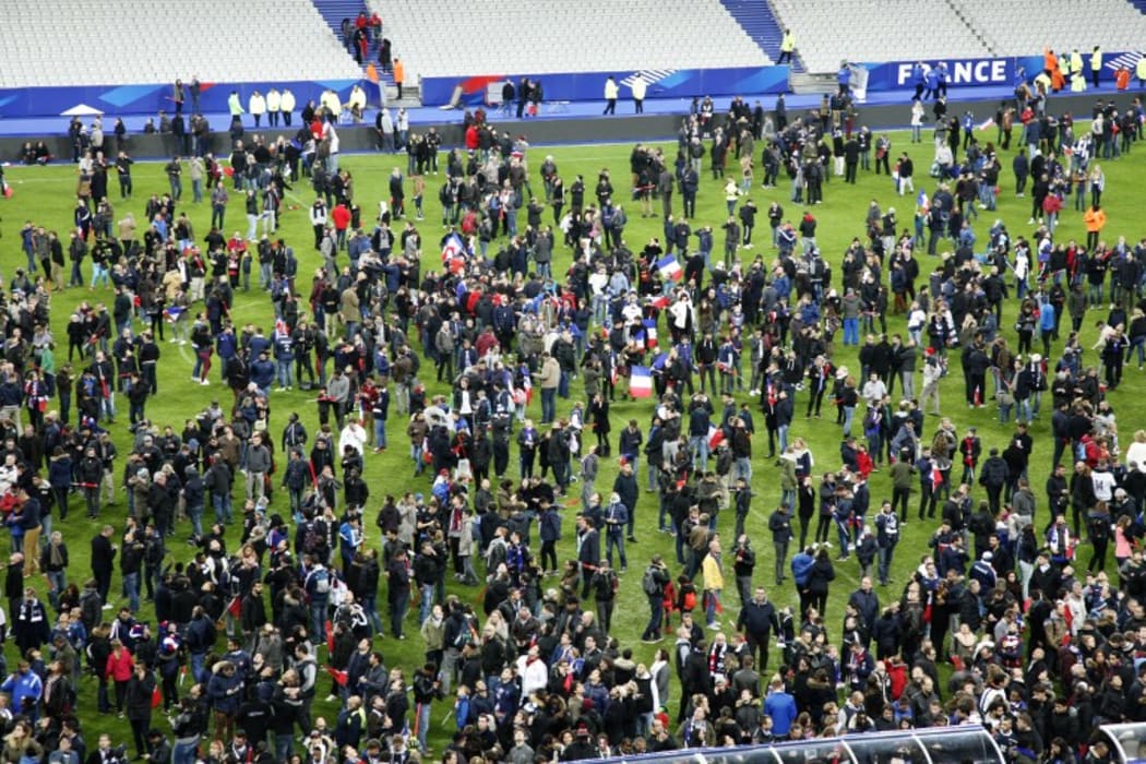 Spectators wait on the pitch of the Stade de France stadium in Seine-Saint-Denis