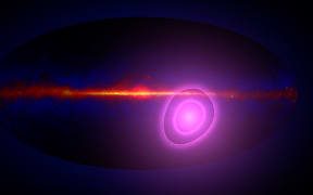 This artist’s concept shows the entire sky in gamma rays with magenta circles illustrating the uncertainty in the direction from which more high-energy gamma rays than average seem to be arriving. In this view, the plane of our galaxy runs across the middle of the map. The circles enclose regions with a 68% (inner) and a 95% chance of containing the origin of these gamma rays.